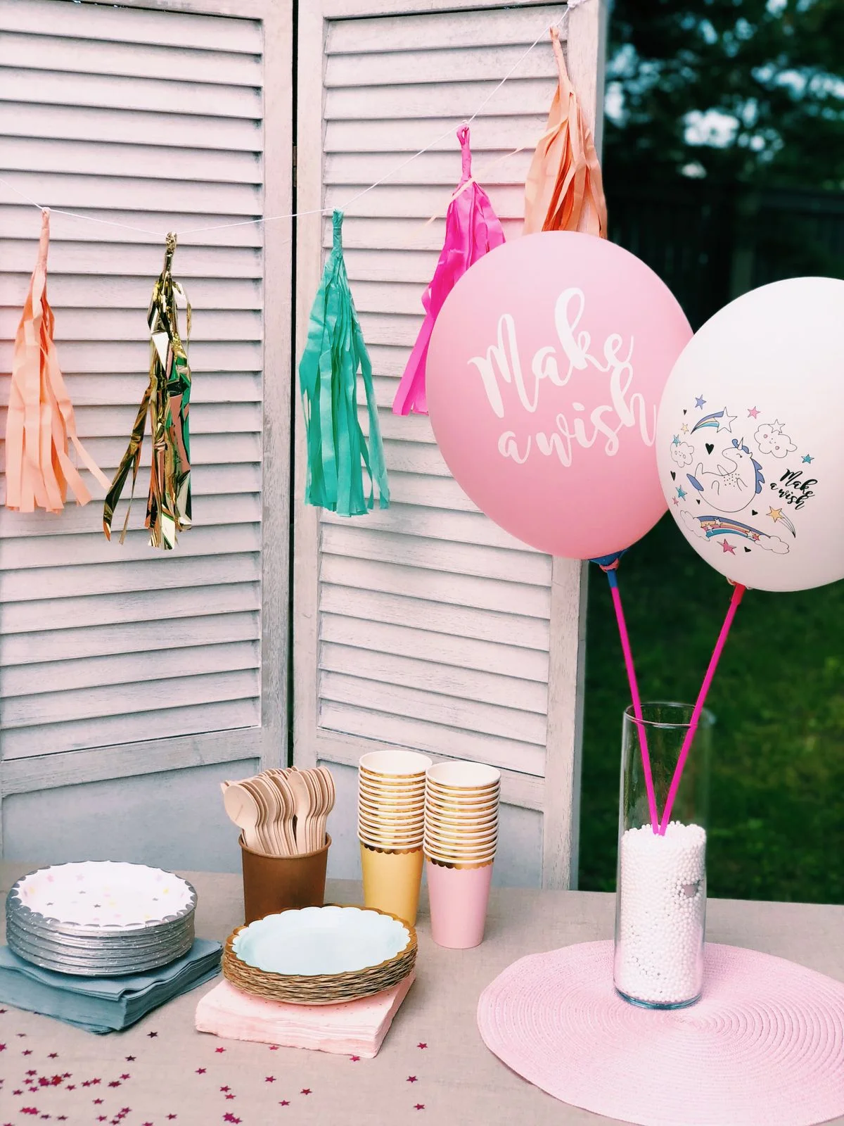 Fotografía de stock: mesa exterior de fiesta rosa con globos y guirnalda de flecos